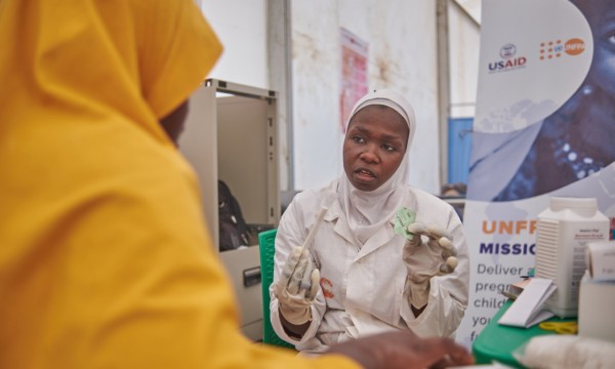 A healthcare worker attends to a mother during an ante natal care visit in UNFPA flood response tent in  Bakasi IDP Camp Maiduguri, Borno, Nigeria.